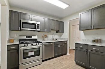 A kitchen with dark cabinets and stainless steel appliances.