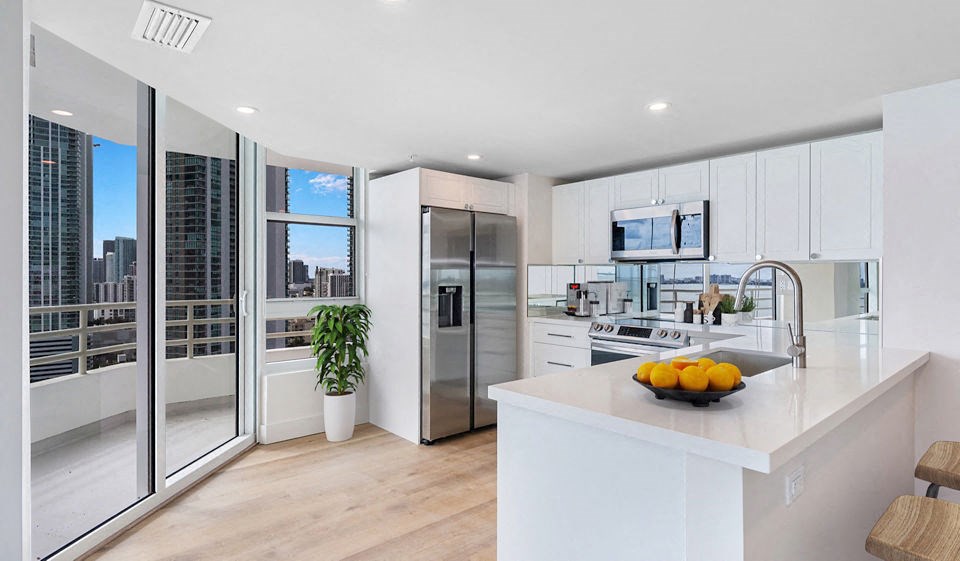 a white kitchen with a large island and a stainless steel refrigerator at The Hamilton, Florida