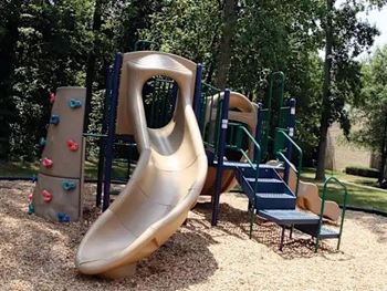 A playground with a slide, climbing wall, and seating area.