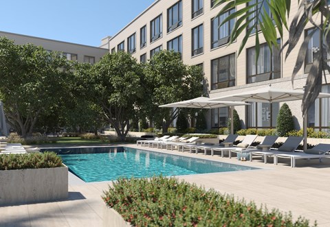 A pool surrounded by chairs and trees in front of a building.