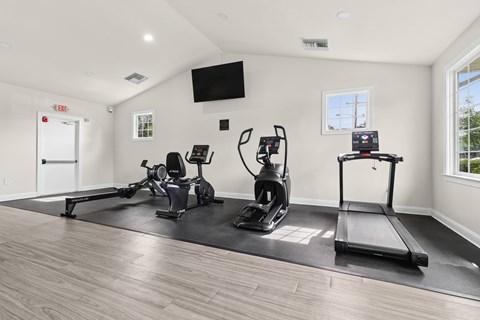 A spacious home gym with a treadmill, rowing machine, and stationary bike.