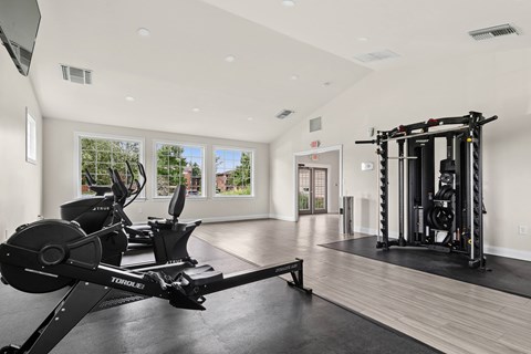 A home gym with a rowing machine and a squat rack.