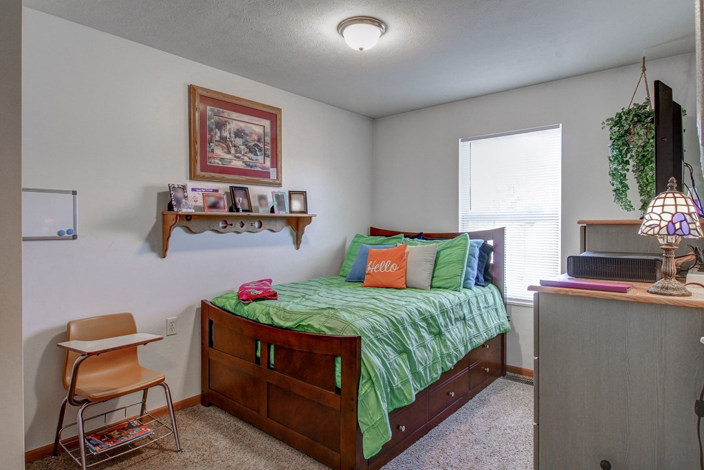 a bedroom with a bed and a desk and a window