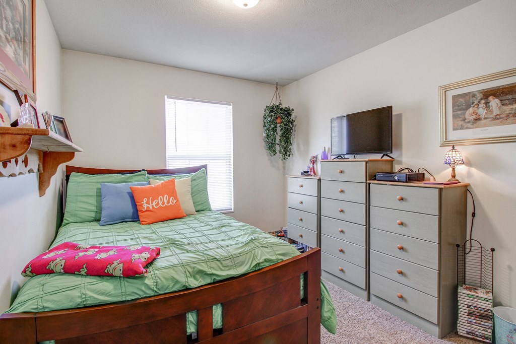 a bedroom with a bed and a dresser with a tv