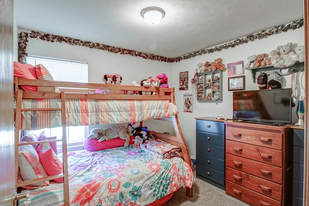 a bedroom with bunk beds and a dresser with a tv