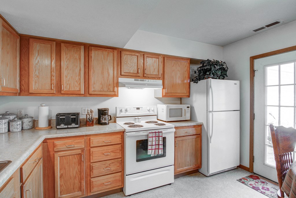 a kitchen with white appliances and wooden cabinets