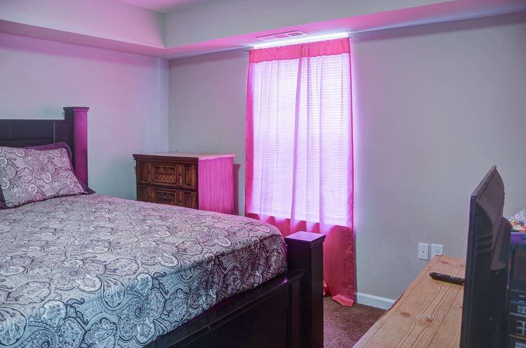 a bedroom with a bed and a dresser and a window