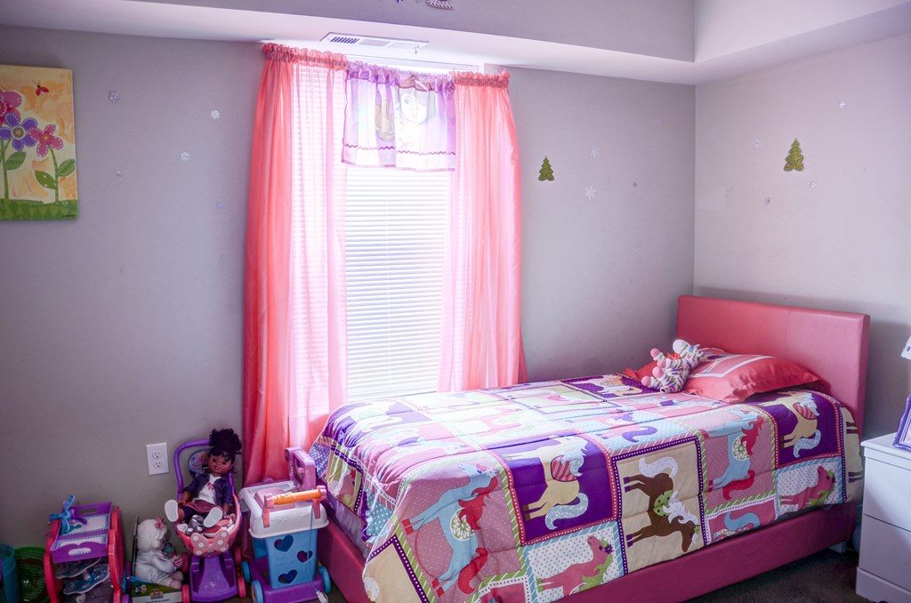 a bedroom with a bed and a window with pink curtains