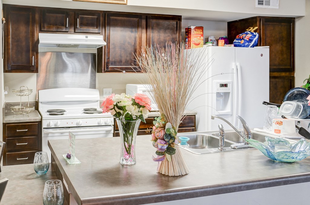 a kitchen with white appliances and flowers on the counter
