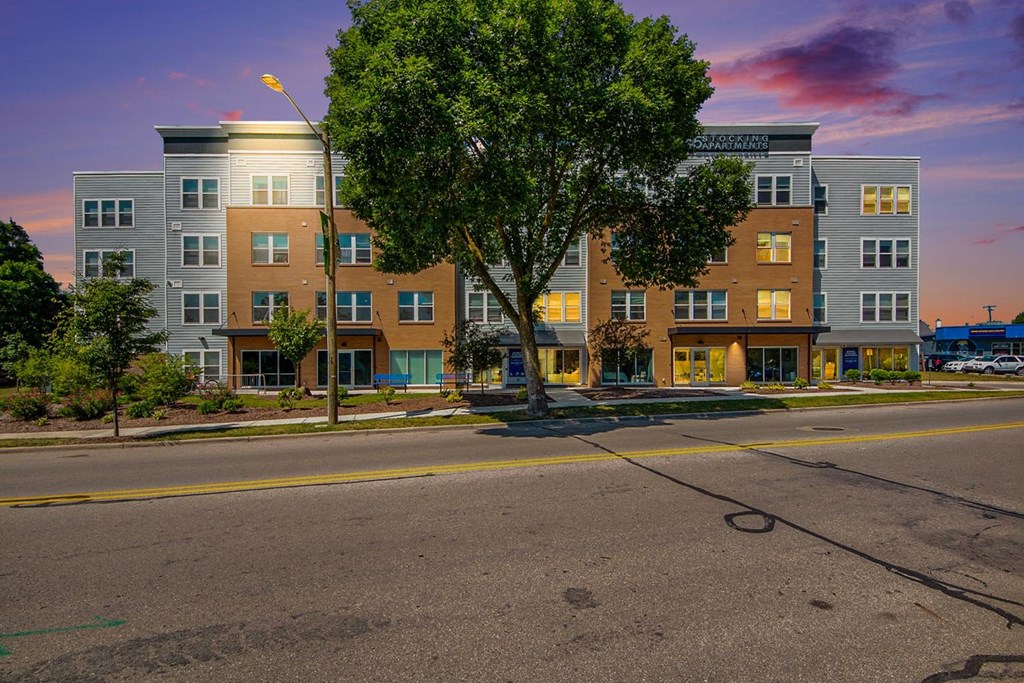 a city street with an apartment building at sunset