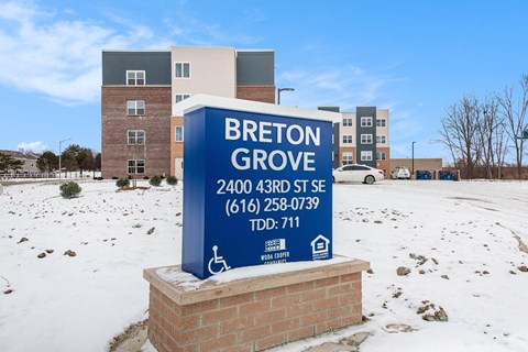 A sign for Breton Grove is in front of a building.