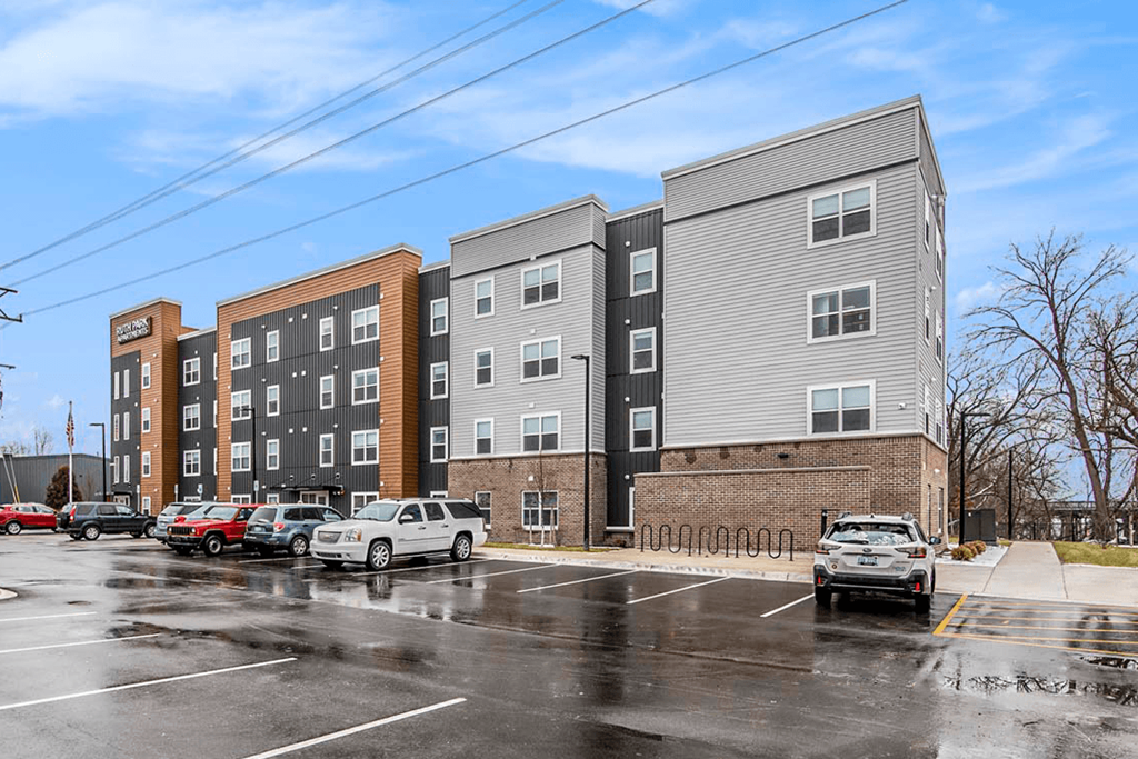 an image of an apartment building with cars parked in a parking lot