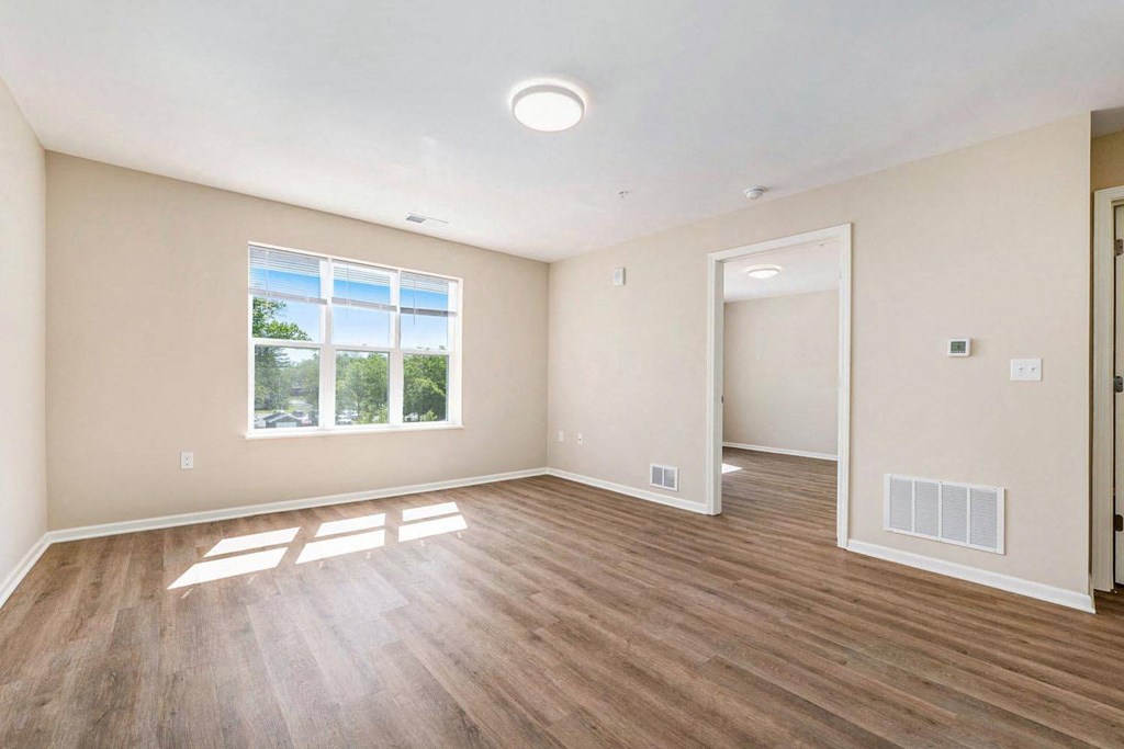an empty living room with wood flooring and a window