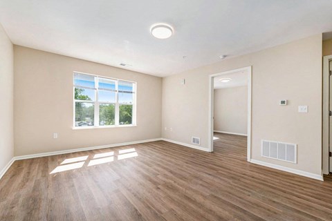 an empty living room with wood flooring and a window