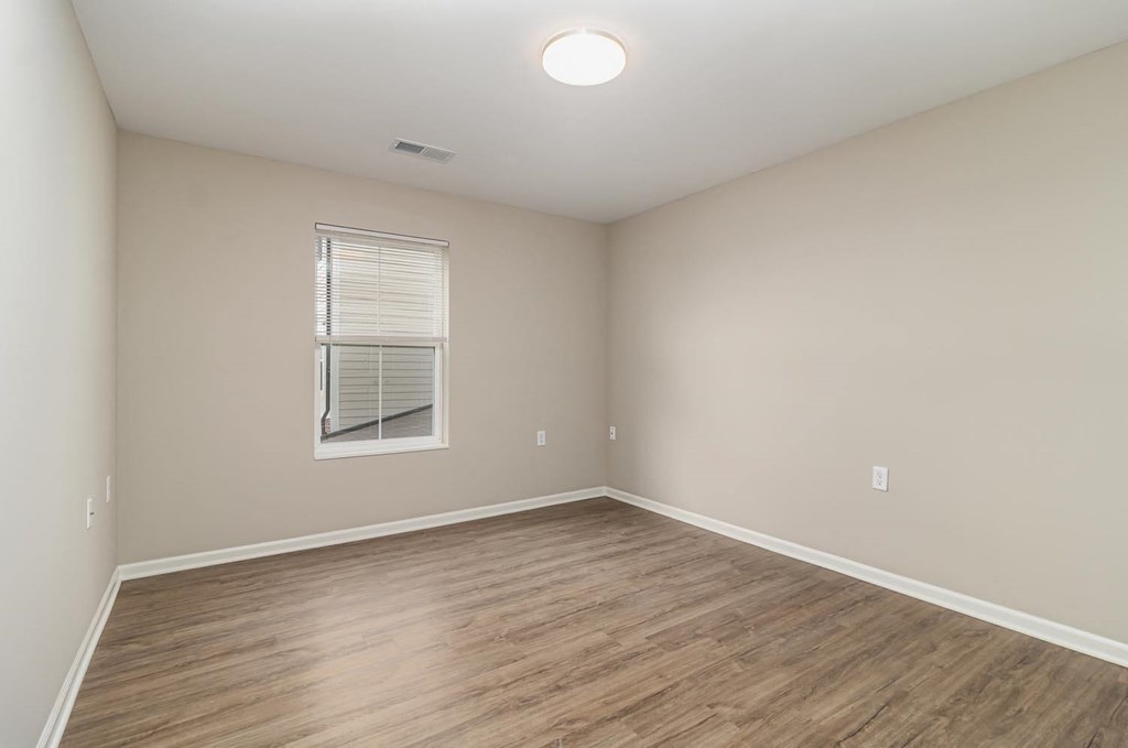 an empty living room with wood floors and a window