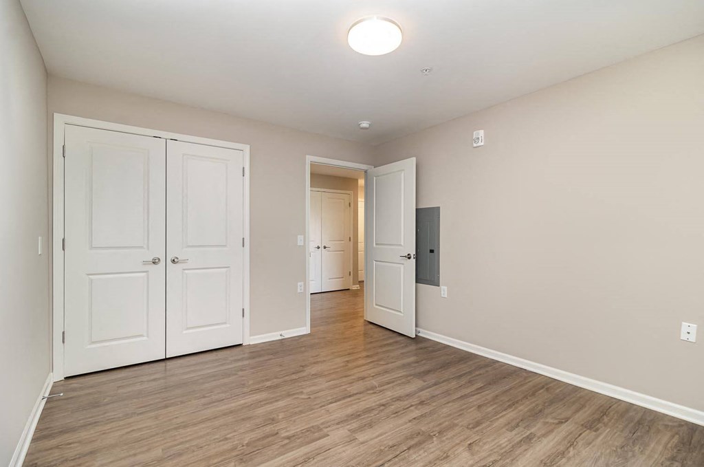 an empty living room with white doors and a door to a hallway