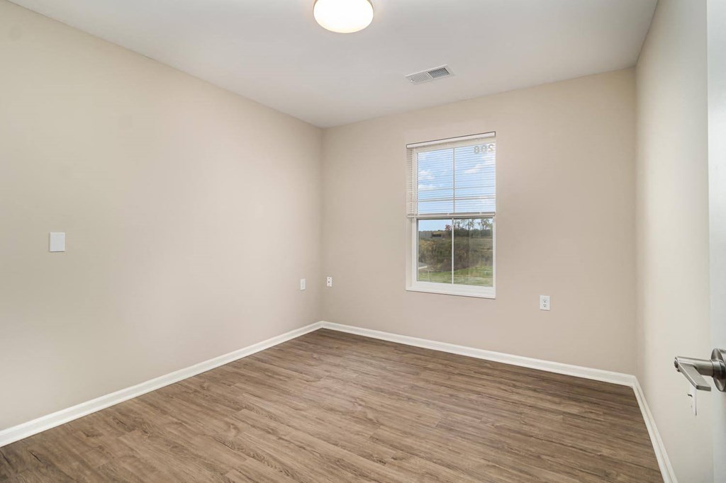 an empty room with wood floors and a window