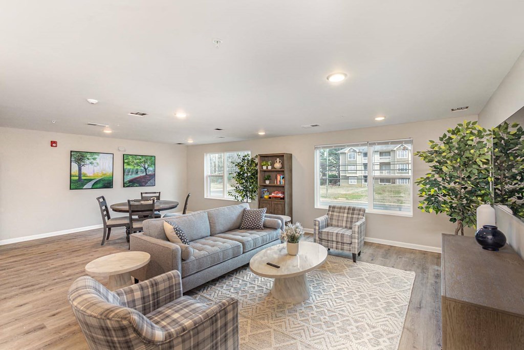 A living room with a grey couch, a coffee table, and a large window.
