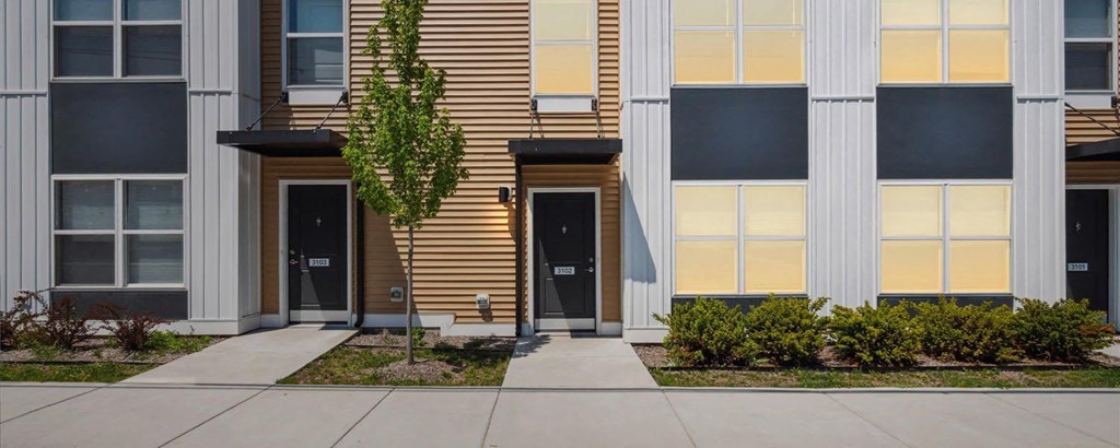 a picture of a building with two doors and a sidewalk in front of it