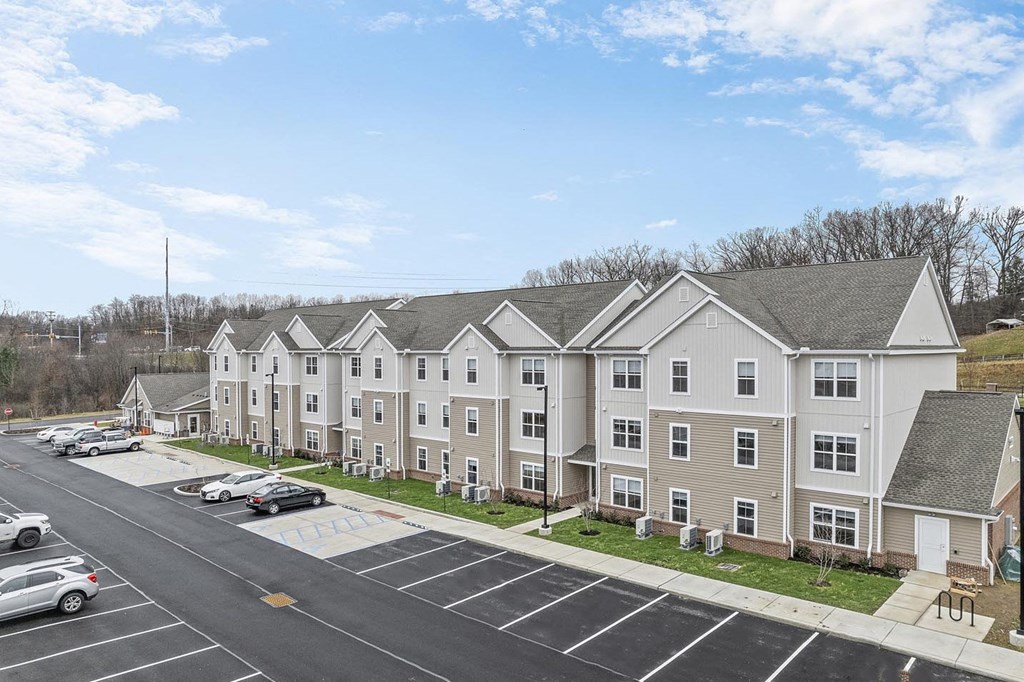 A parking lot in front of a building with cars parked.