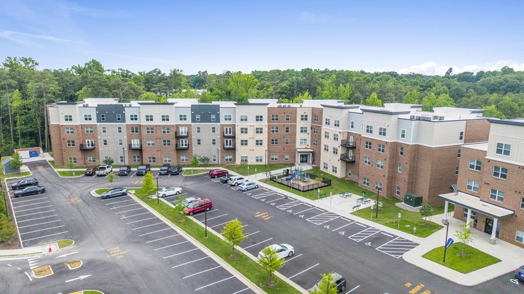 A parking lot in front of a multi-story apartment building.