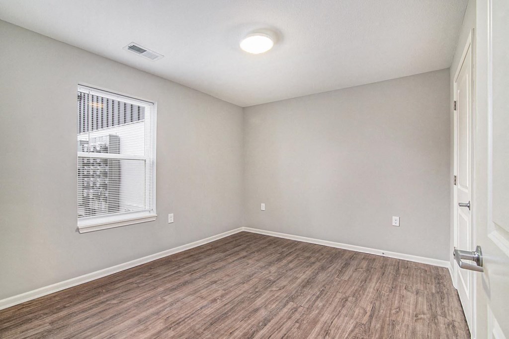 an empty living room with a window and wood flooring