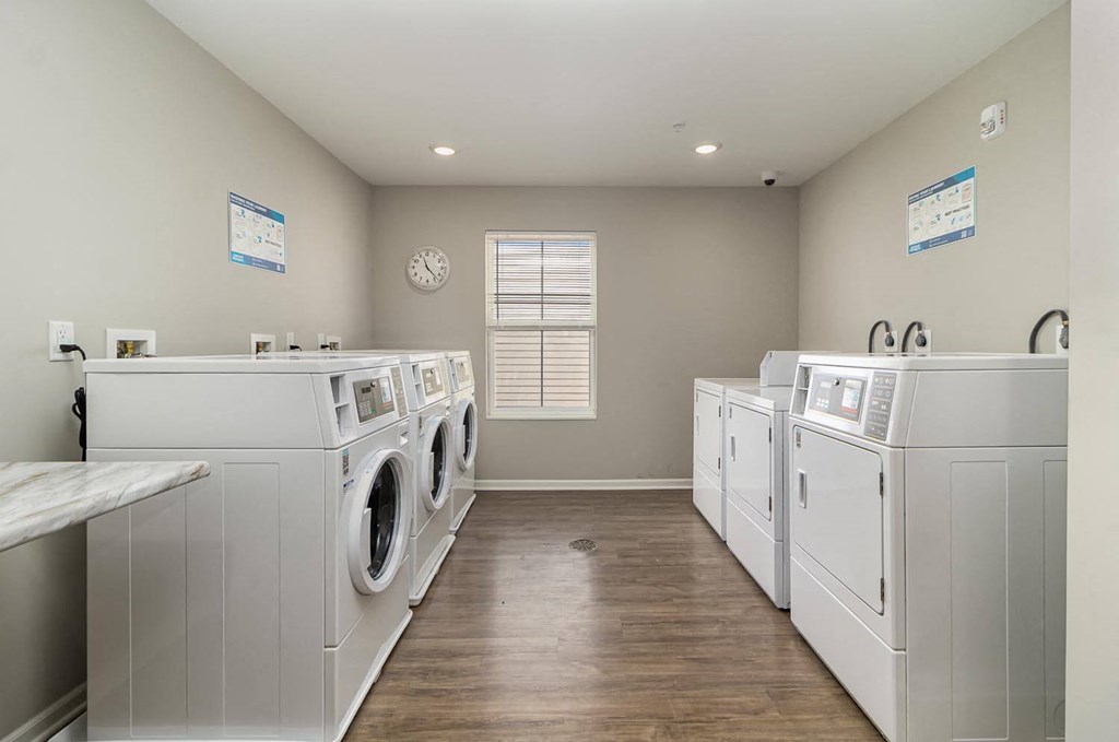 a washer and dryer room with a row of washes and dryers