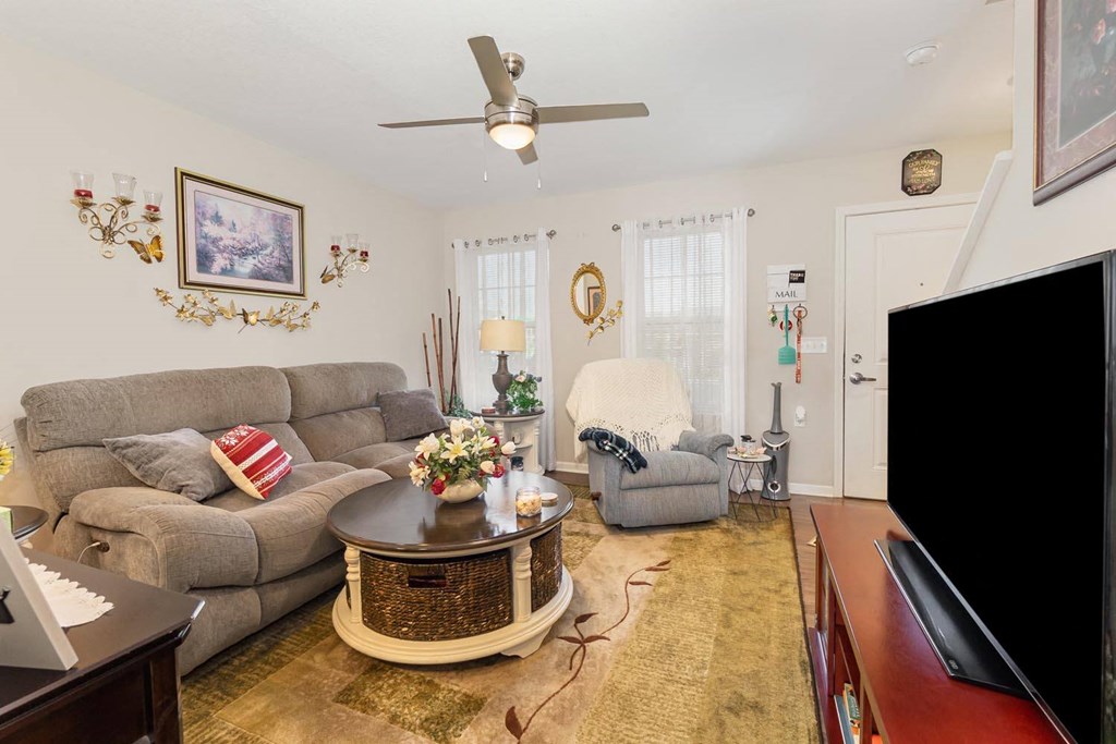 a living room with white walls and a ceiling fan
