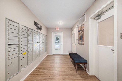 A long hallway with a bench and mailboxes on the wall.