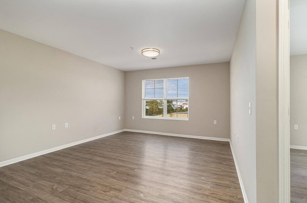 an empty living room with wood floors and a window
