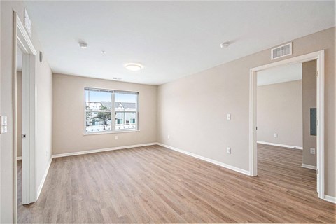 A spacious room with wooden flooring and a window overlooking a cityscape.
