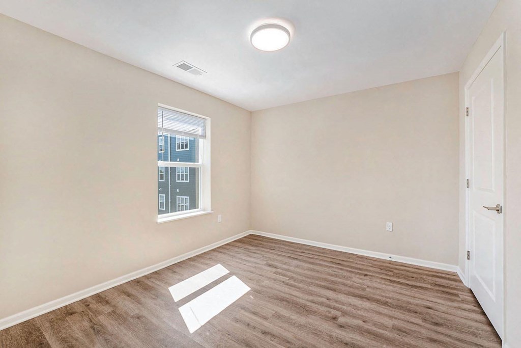 an empty living room with wood flooring and a window