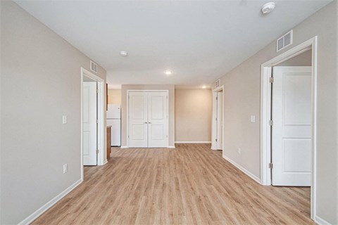 A room with white walls and wooden flooring with a door on the right.