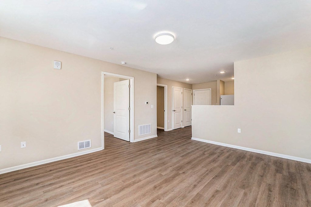 a spacious living room with a hard wood floor and white walls
