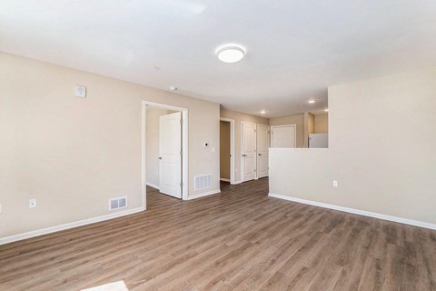 a spacious living room with a hard wood floor and white walls