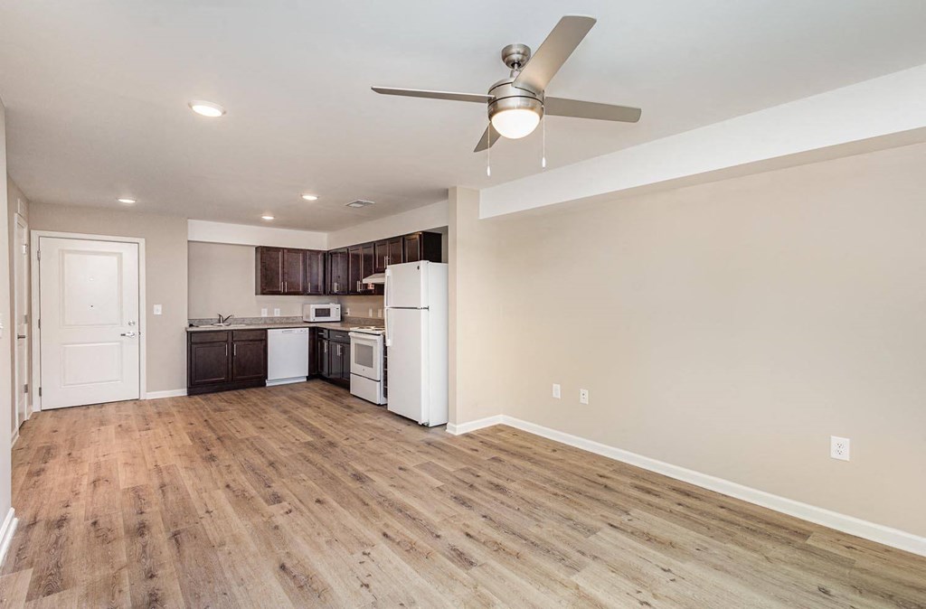 A kitchen with a white fridge and wooden floors.