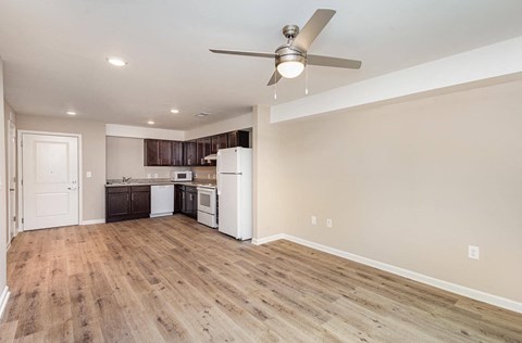 A kitchen with a white fridge and wooden floors.