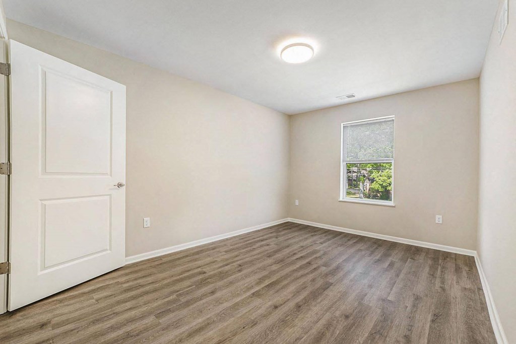 an empty living room with a white door and a window