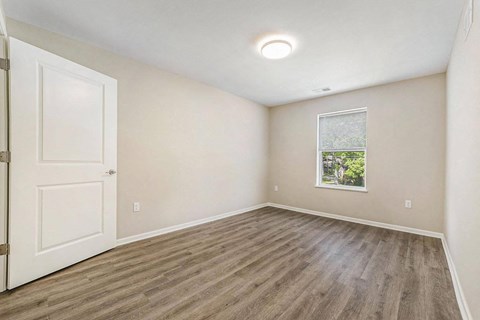 an empty living room with a white door and a window