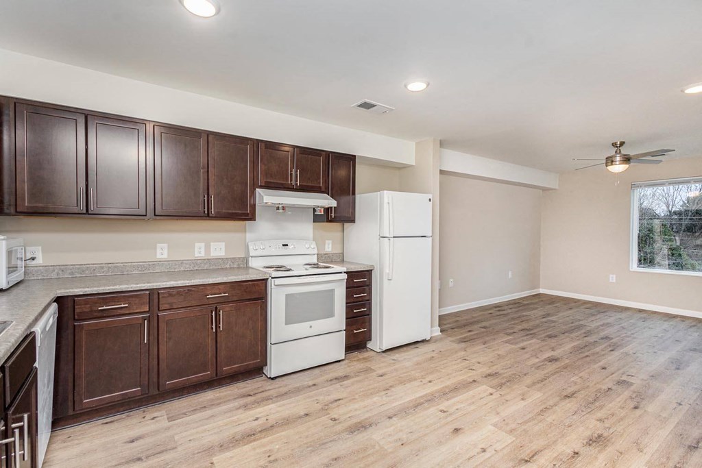 A kitchen with white appliances and wooden cabinets.