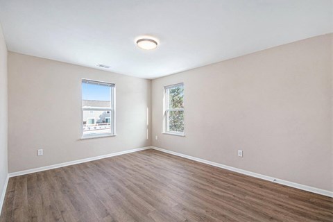A room with wooden floors and two windows.