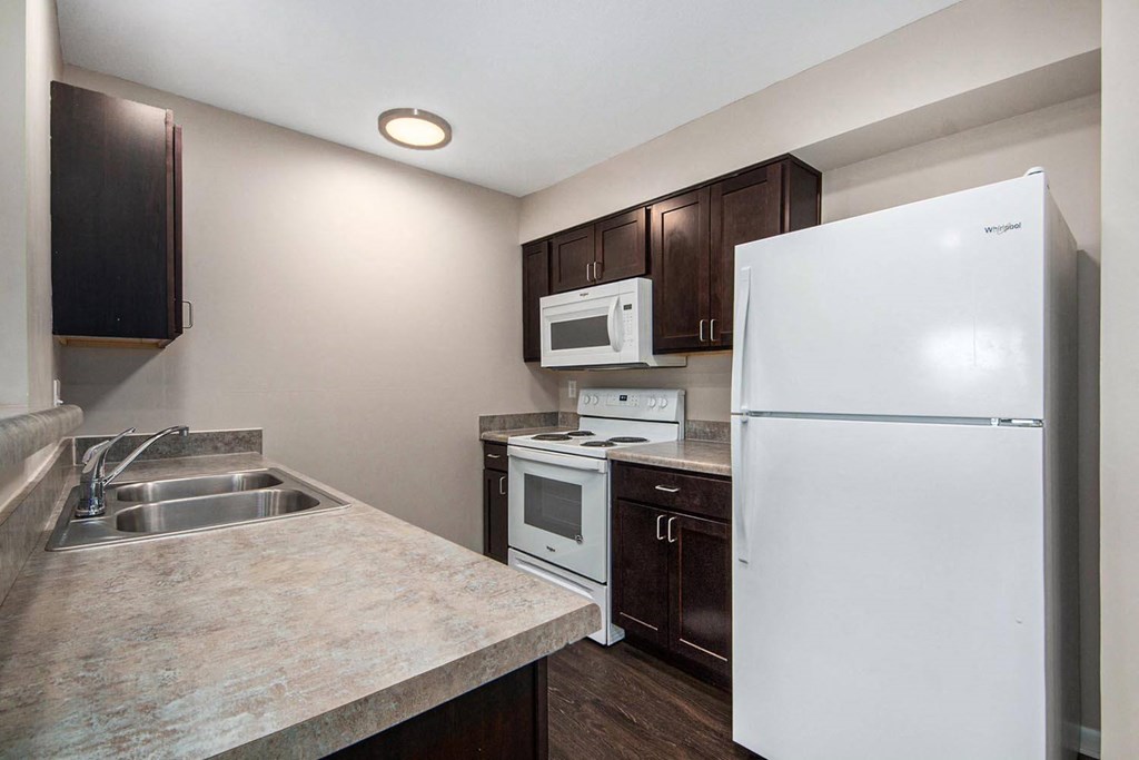 a kitchen with white appliances and dark wood cabinets