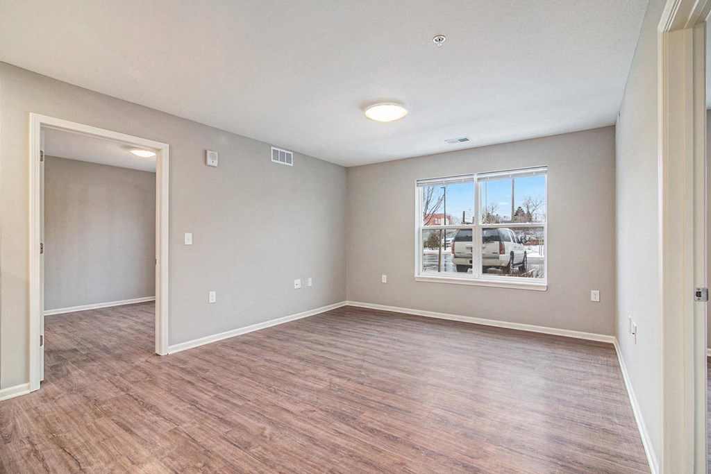 an empty living room with wood floors and a window