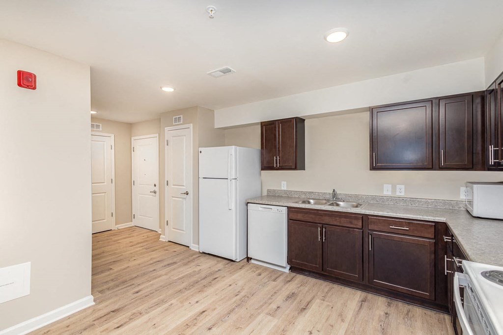 A kitchen with white appliances and brown cabinets.