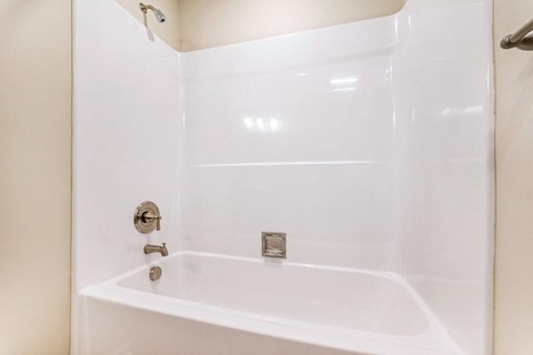 a white bathroom with a tub and a faucet