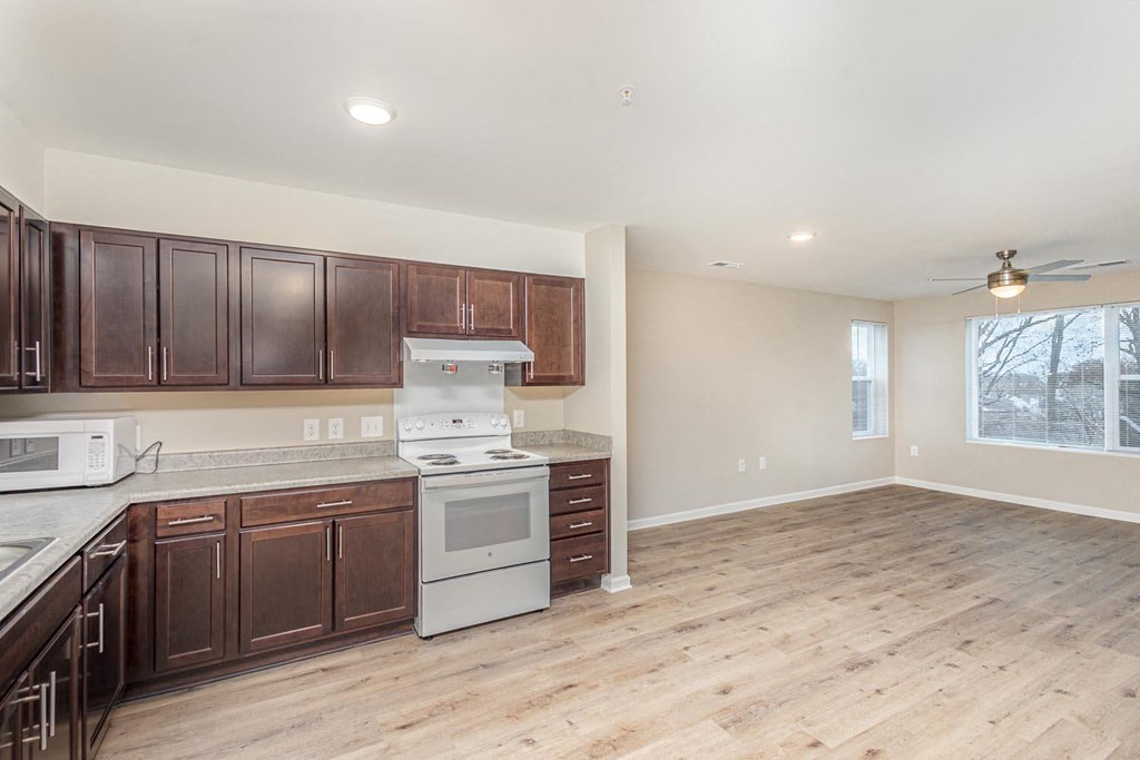 A kitchen with wooden cabinets and a white stove top oven.