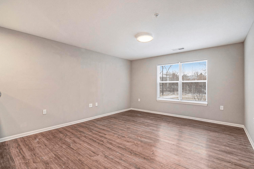 an empty living room with wood flooring and a window