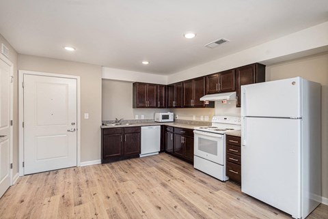 A kitchen with white appliances and wooden floors.