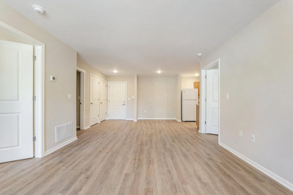 the living room and kitchen of a new home with white walls and wood flooring