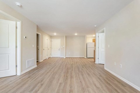 the living room and kitchen of a new home with white walls and wood flooring